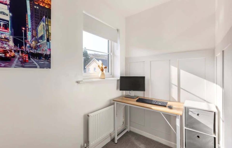 This stylish office nook features a wooden desk, computer setup, and colorful cityscape art. Clean lines and natural light create the perfect environment for work or study.