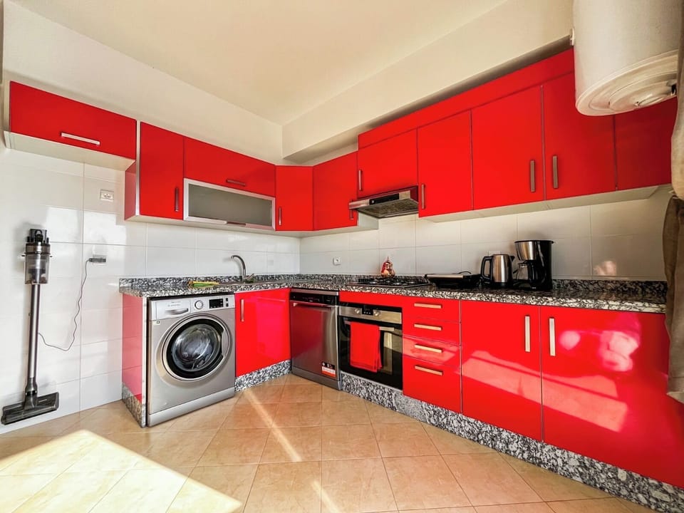 Kitchen with modern appliances including washer (8KG - 68L capacity), dishwasher, oven, stove top and vent, hot water heater (40L capacity), coffee maker, kettle, panini press, and cordless vacuum