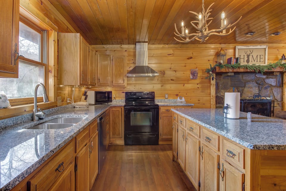 Your mountain kitchen welcomes you with warm wood cabinets, granite countertops, and rustic charm enhanced by an antler chandelier.