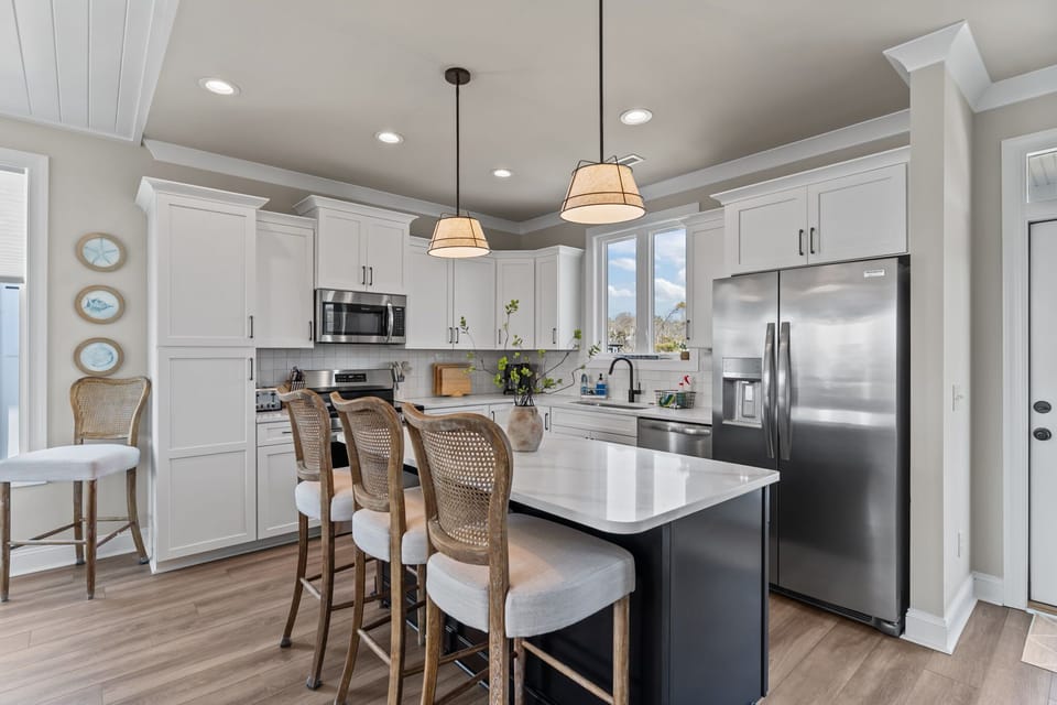 Bright Coastal Kitchen w/ Stainless Steel Refrigerator, Built-In Microwave, Electric Range Oven, Dishwasher, Large Island Seating, Pendant Lighting, and Natural Light