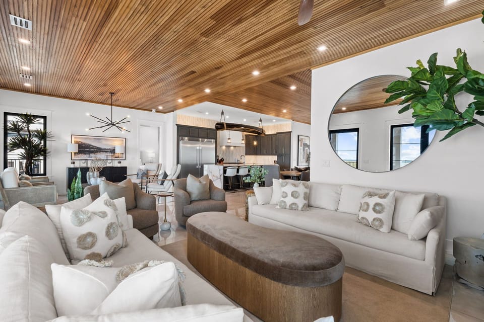 Sink into plush sofas beneath striking wood ceilings and unwind in your spacious living area, where natural light and elegant design create the perfect retreat.