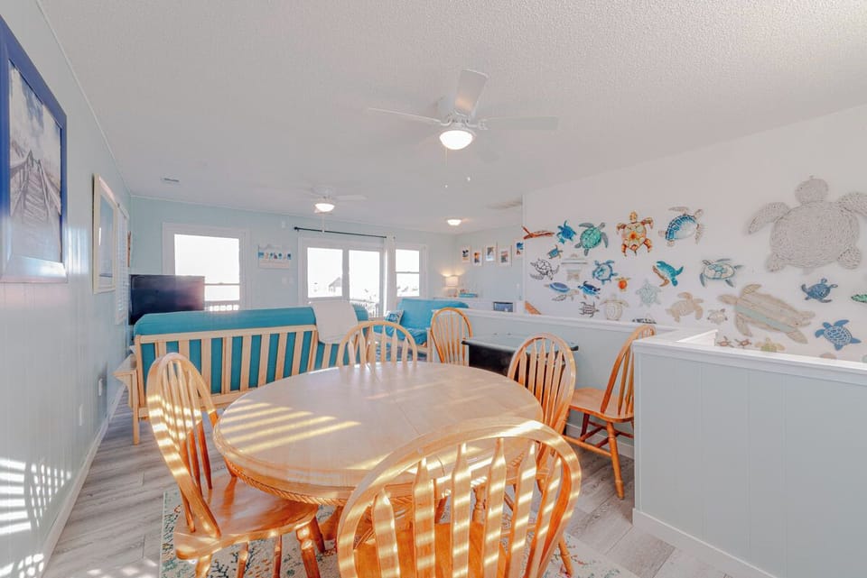Gather around this sunny dining table where ocean-themed art creates a playful coastal atmosphere for your beach vacation meals.