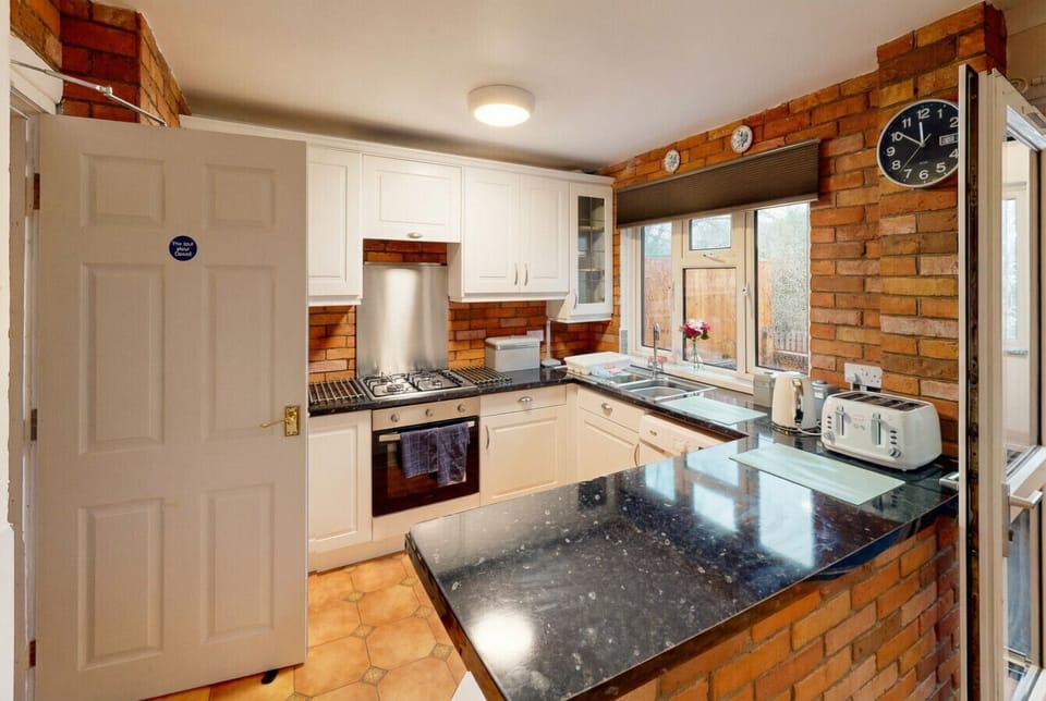 A well-equipped kitchen with granite worktops, a gas hob, and exposed brick character walls.