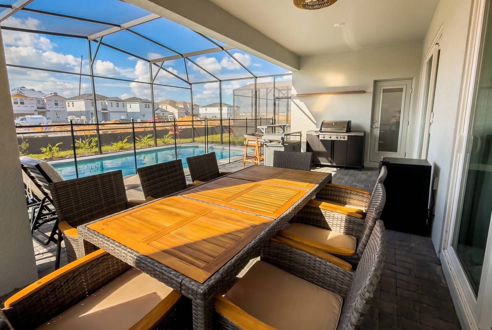 Spacious covered outdoor area featuring a dining table, grill, and private screened pool. A comfortable setting for outdoor meals, family barbecues, and relaxing moments by the pool.