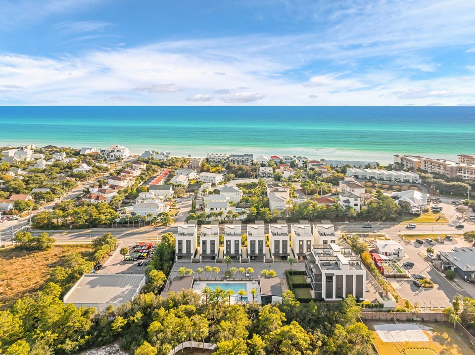 Aerial view of beachfront property development showcasing modern architecture and pristine turquoise waters nearby.