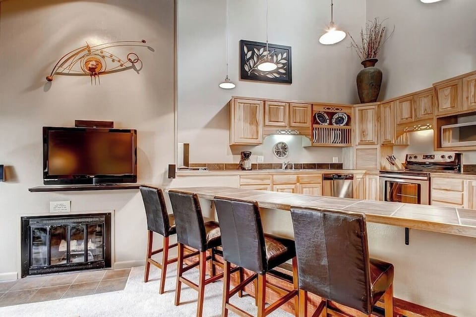 Gather around your spacious breakfast bar where warm wood finishes and modern appliances create the perfect spot for morning coffee or casual meals.