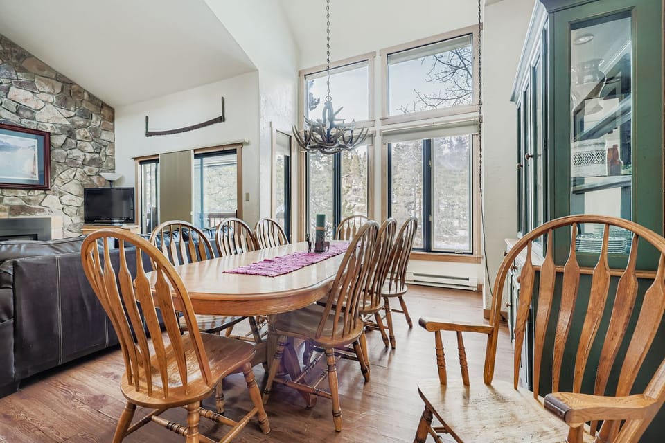 Gather around this spacious dining table where mountain views through floor-to-ceiling windows create the perfect backdrop for your memorable meals together.