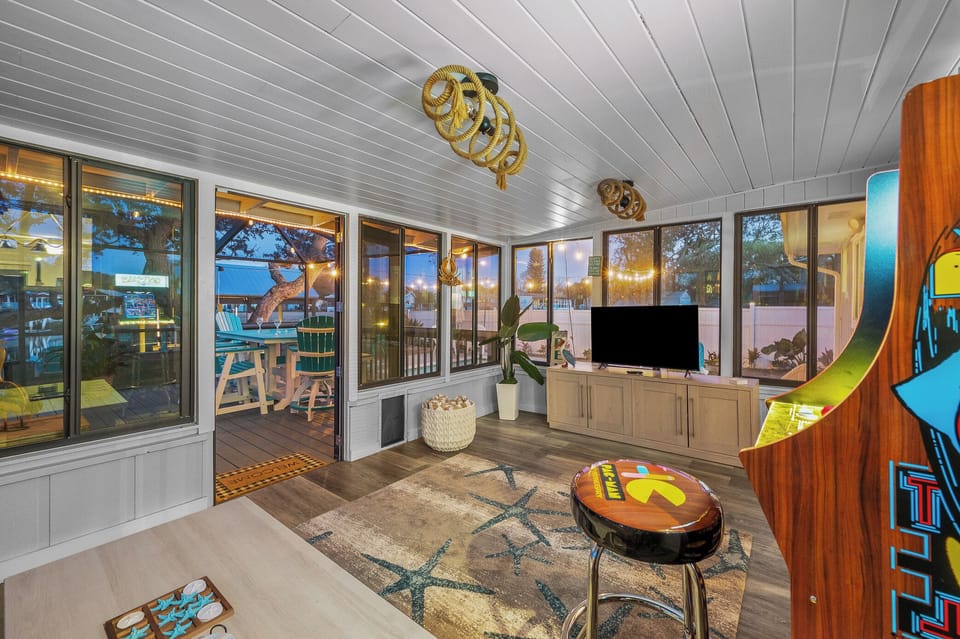 Sunroom with arcade game, TV, and views of the patio
