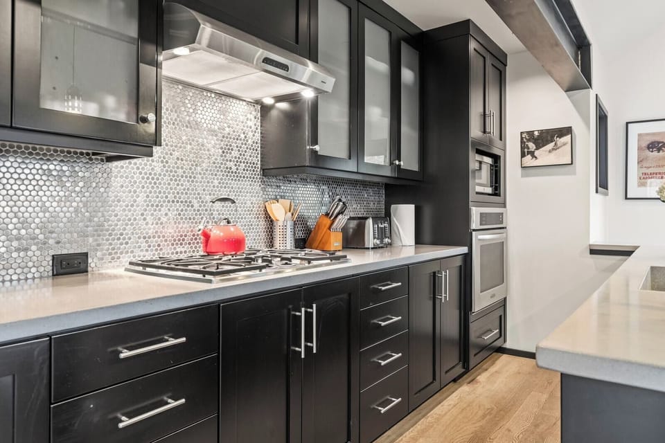 Full-length cabinetry, tile backsplash, and streamlined design offer both beauty and utility.