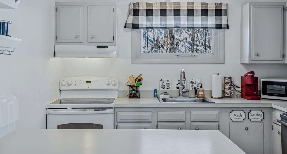 Kitchen with electric stove, ample counter space, and buffalo check accents