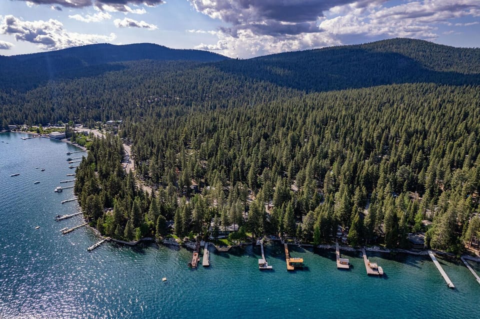 Scenic aerial view of the North Lake Tahoe shoreline surrounded by forested mountains, highlighting the natural beauty near the property.