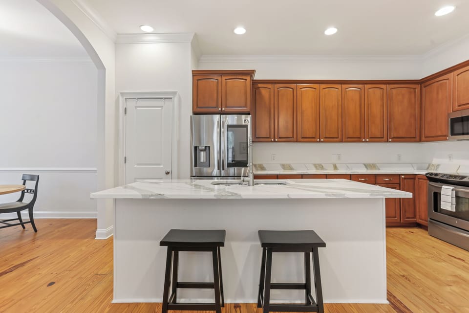 The bright kitchen features a large island with two barstools — a perfect spot for morning coffee or casual meals.
