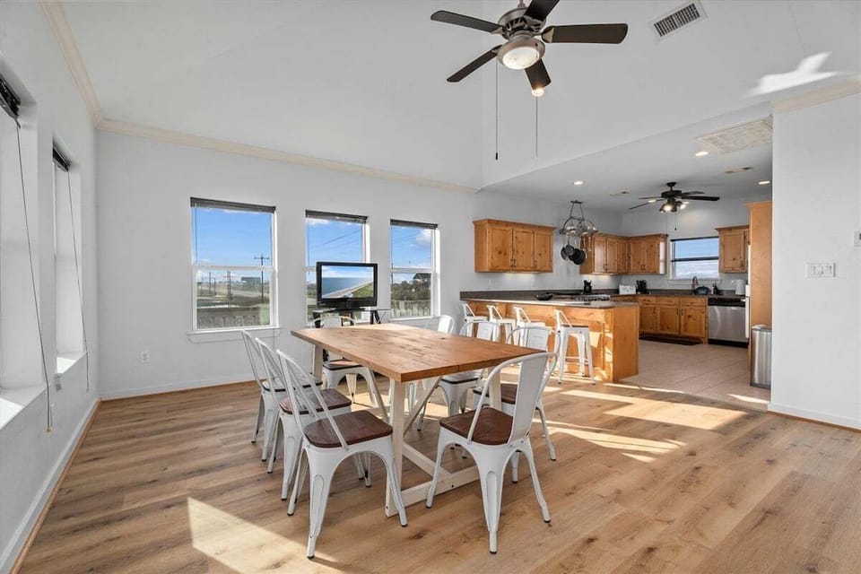 Dining area with large table, natural lighting, and open kitchen layout ideal for group meals.