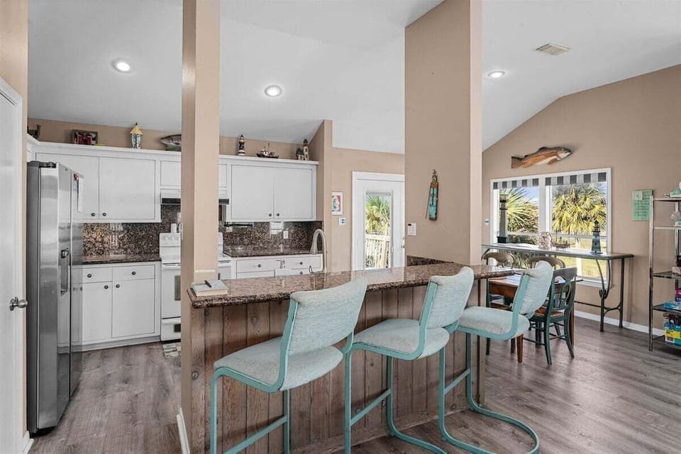 Spacious kitchen and breakfast bar with multiple stools and open sightlines throughout the home. Perfect for gathering while preparing meals.