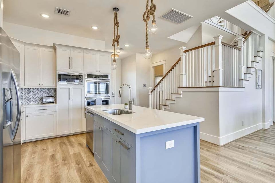 Fully equipped chef's kitchen featuring quartz countertops, spacious island, and modern lighting fixtures.