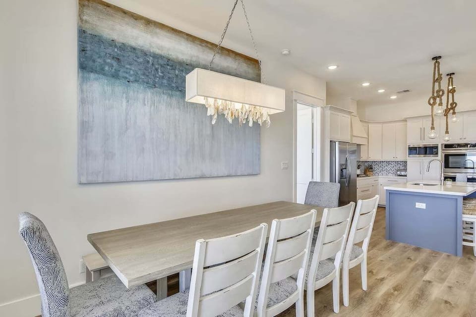 Dining space with statement lighting and contemporary coastal artwork, perfect for family gatherings.