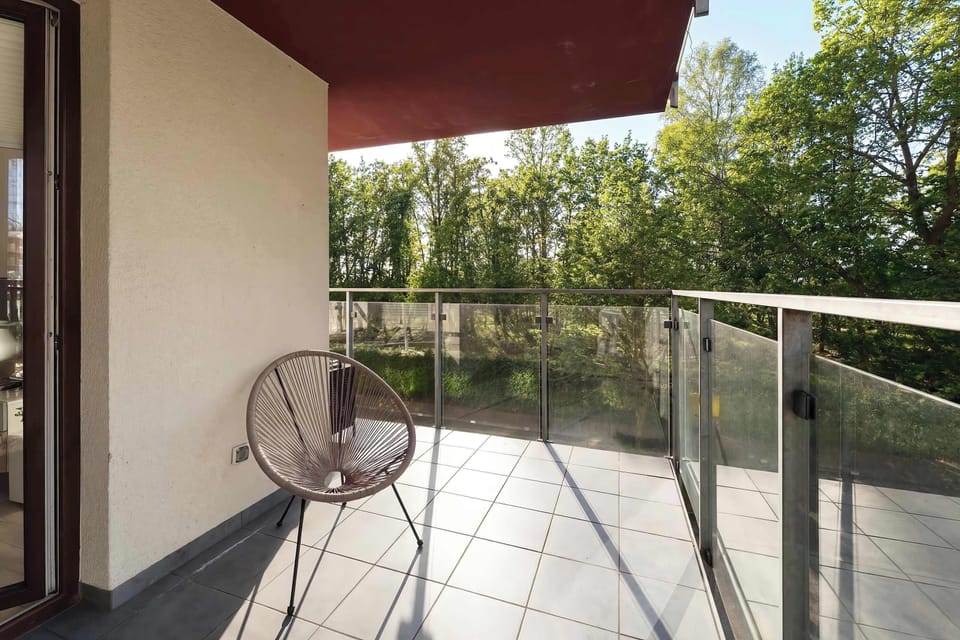 A high-angle shot of the balcony reveals its generous size and high-quality grey tiling. It is an ideal spot for enjoying fresh air in a peaceful, leafy setting.