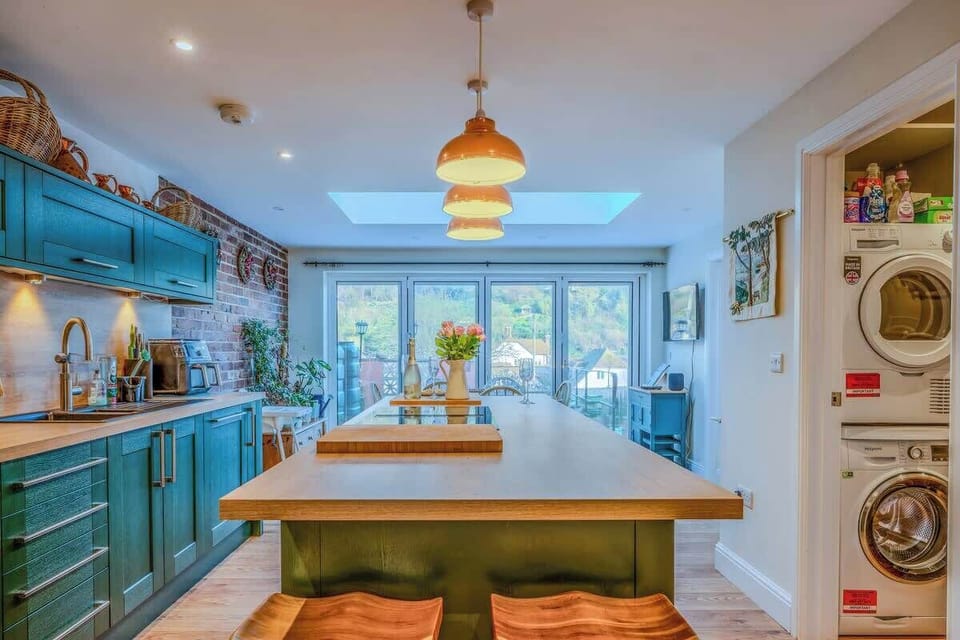 A stylish open-plan kitchen, dining and lounge with a sociable kitchen island, creating a warm and inviting space for entertaining, dining, and unwinding