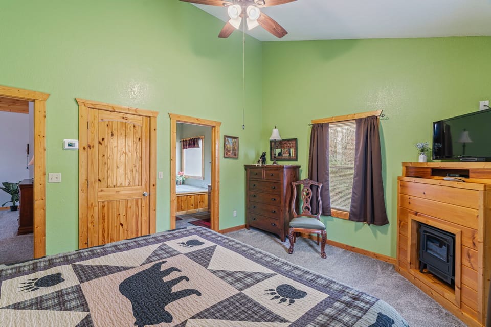 Unwind in your cozy bedroom with rustic charm, featuring warm wood accents, a ceiling fan for comfort, and peaceful green walls that invite relaxation.