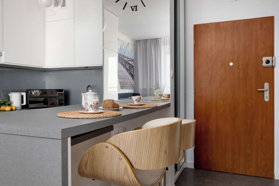 A functional bar area separating the kitchenette from the room, equipped with woven stools. Cups are placed on the countertop, inviting you to relax with a warm drink.