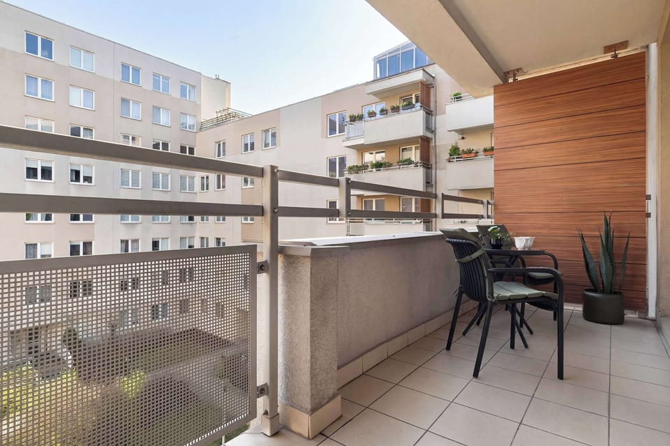 Another view of the balcony, emphasizing its size and the possibility of relaxing on sunny days. The floor is covered with light-colored tiles that blend well with the building's facade.