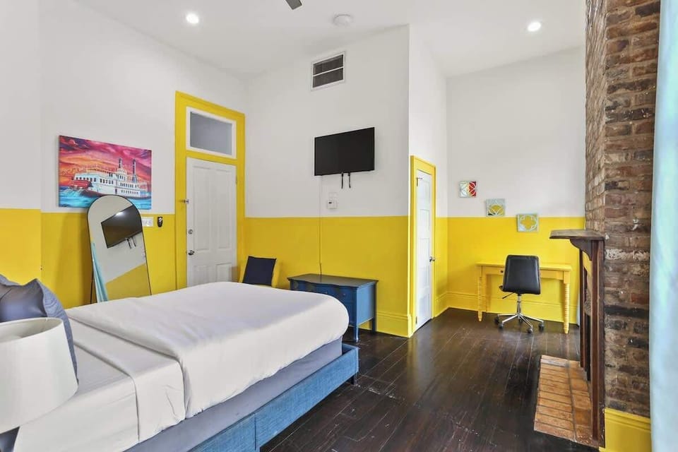 Bright, cheerful bedroom with a queen bed, Smart TV, and dedicated workspace. High ceilings, bold accents, and thoughtful layout create a comfortable retreat for rest or remote work.