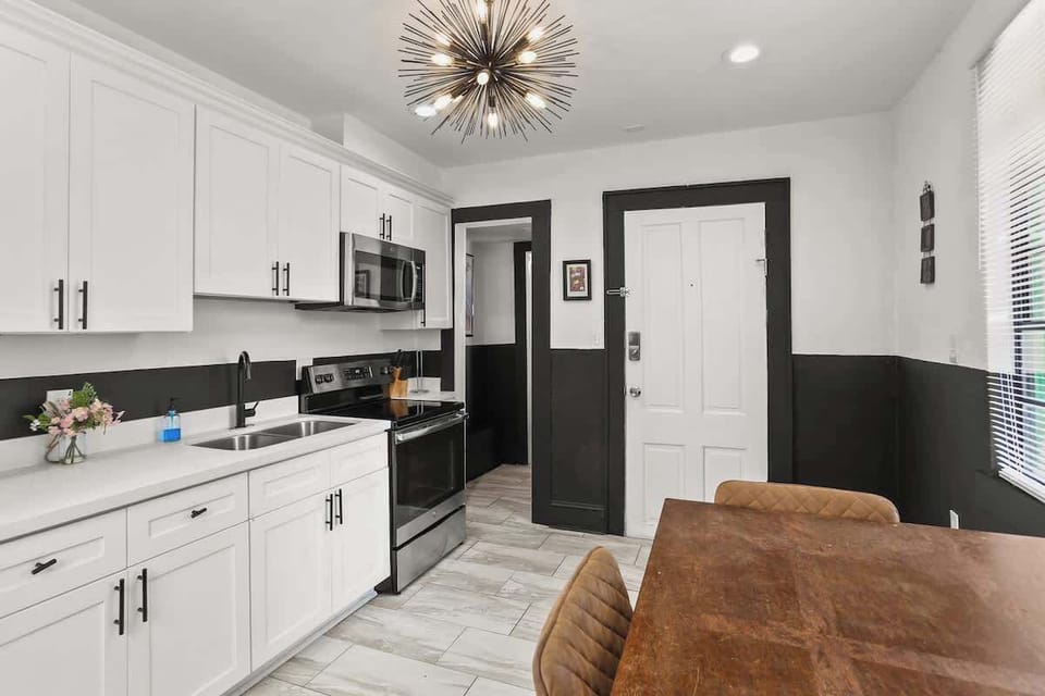 Modern, fully equipped kitchen with updated appliances and a dedicated dining table—perfect for preparing meals, enjoying takeout, or gathering together before heading out to explore New Orleans.