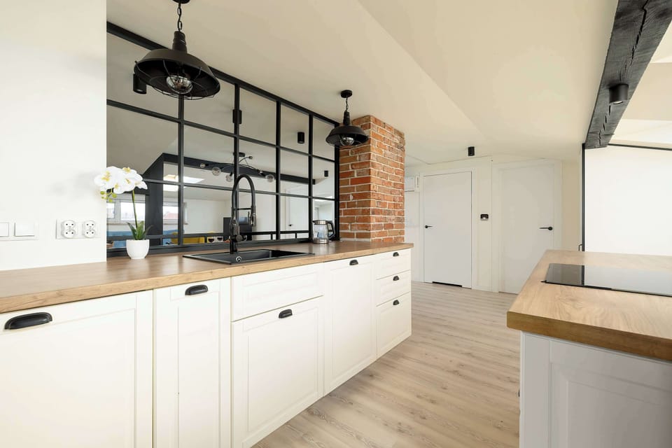 A full kitchen perspective demonstrates the ample storage provided by the white handleless cabinets. The open transition to the hallway makes the space feel interconnected and wide.