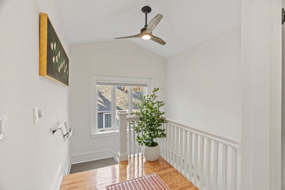 Elegant upstairs landing with warm hardwood floors, natural light, and stylish ceiling fan creates a welcoming transition space.