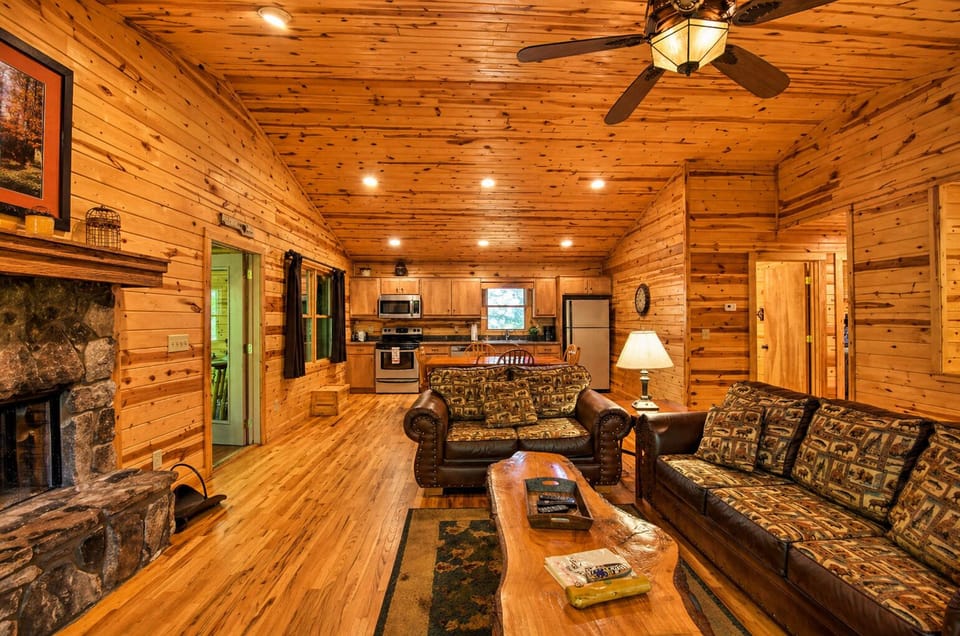 Spacious open-concept living with a cozy stone fireplace, vaulted wood ceilings, and a fully equipped kitchen—perfect for gathering and relaxing.