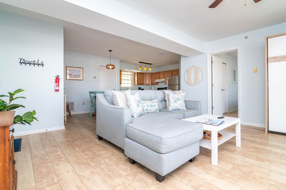 Comfortable living room with a sofa, TV, and a queen-size Murphy bed for additional sleeping space. Sliding doors provide access to the balcony, letting in natural light and coastal breezes.