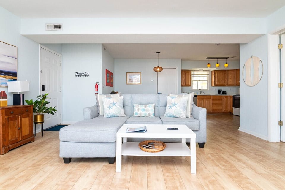 Comfortable living room with a sofa, TV, and a queen-size Murphy bed for additional sleeping space. Sliding doors provide access to the balcony, letting in natural light and coastal breezes.