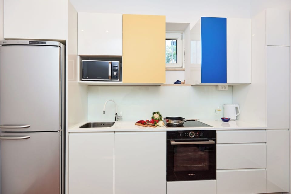 Craft delicious meals in the sleek, fully-equipped kitchen, featuring modern appliances and a clean, minimalist design with bold color accents.