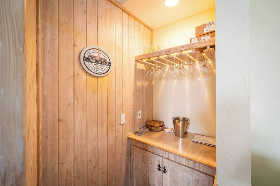 Entryway Storage Nook w/ Vertical Wood Paneling, Built-In Shelf & Cabinet, Hanging Rod w/ Hooks, and Warm Overhead Lighting