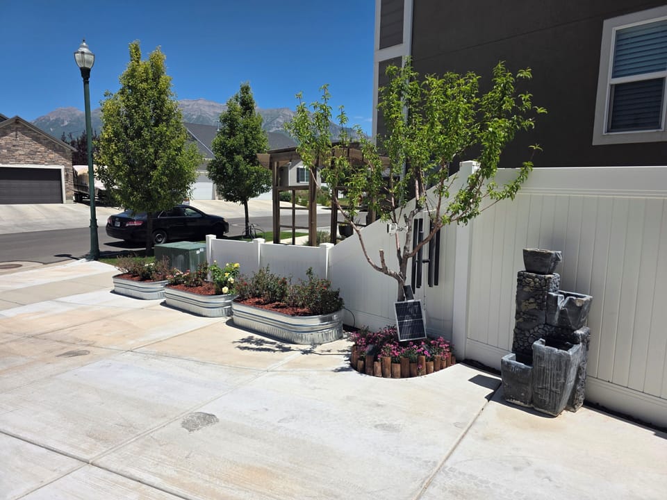 Relaxing side yard with young tree, wind chimes, and stone fountain.