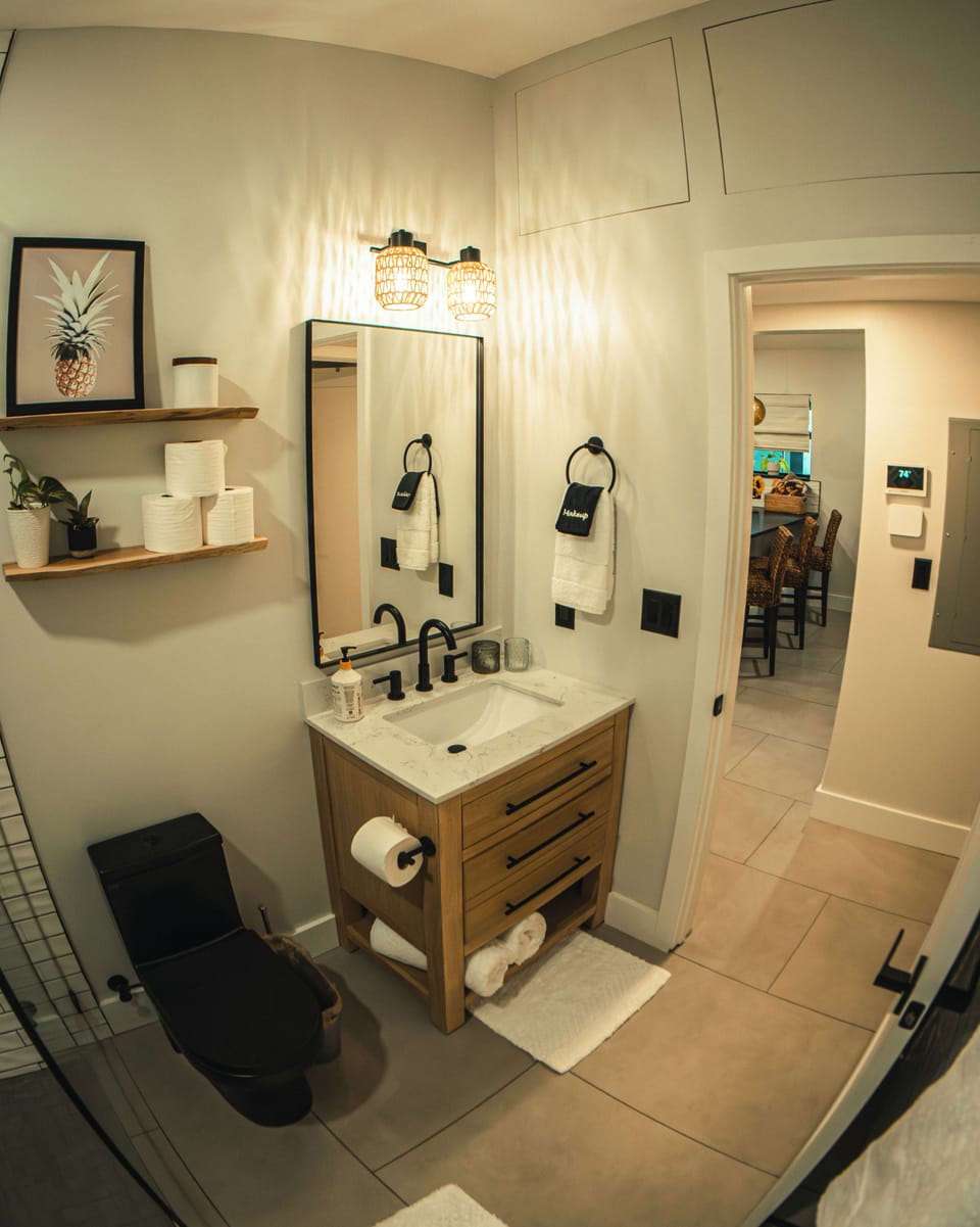 Modern bath with black fixtures, wood vanity & soft lighting
