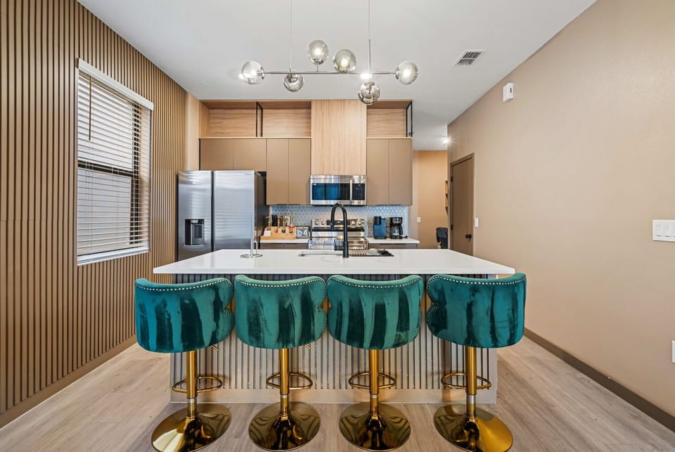Modern kitchen with a large island and teal velvet bar stools for comfortable seating.