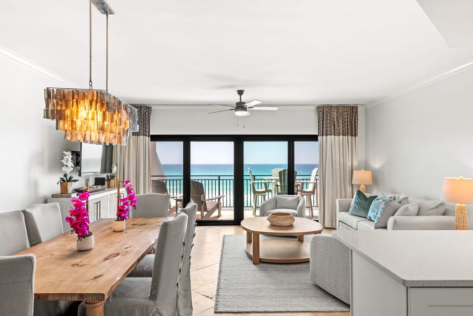 Bright coastal living room with wall-to-wall windows and Gulf front views. 