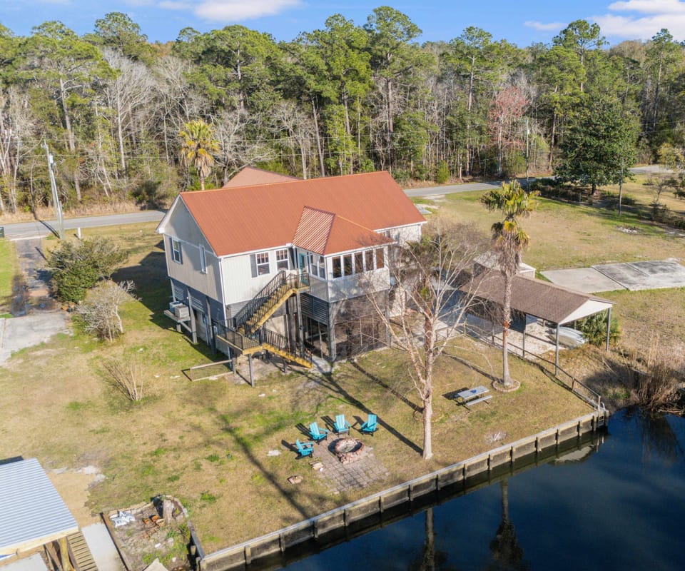 Aerial view showing the home, firepit area, and riverfront setting