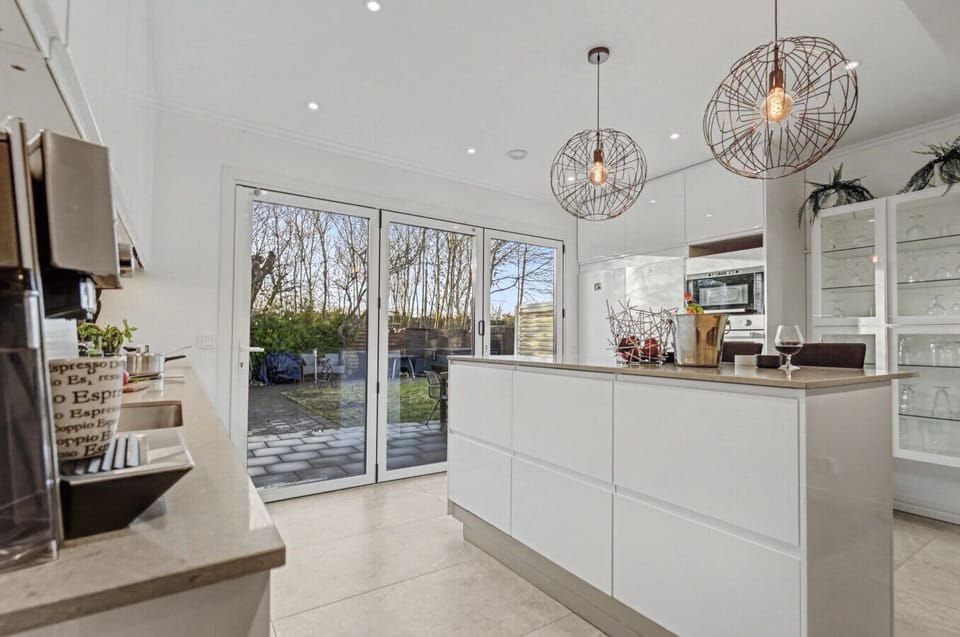 Modern kitchen with island seating and large glass doors leading to the garden.