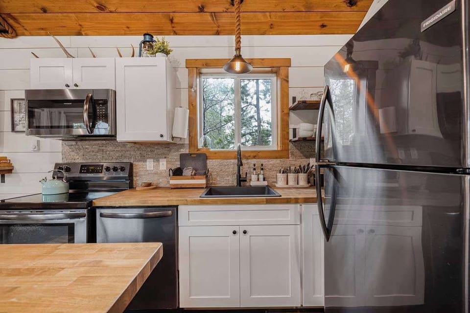 Kitchen with appliances, pots and pans, basic cooking essentials, dishes, and utensils.
