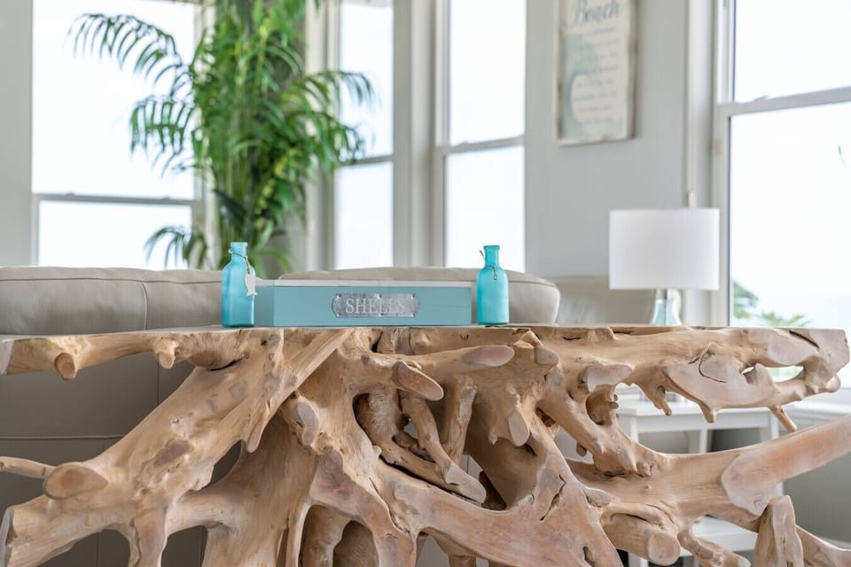 A stunning handcrafted driftwood coffee table serves as the centerpiece of the living room, adding character and coastal charm.