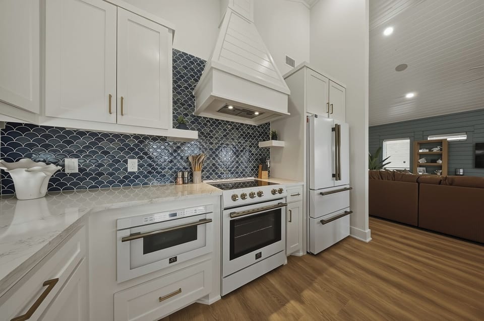 Gather in the airy chef’s kitchen featuring a huge island with seating, bright white cabinetry, and plenty of prep space.