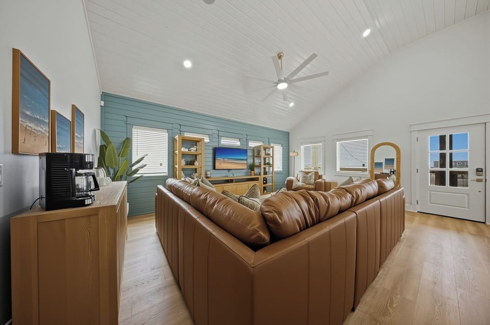Bright, coastal-chic living room with soaring ceilings, oversized seating, and a big-screen TV—made for movie nights, game days, and lounging after the beach.