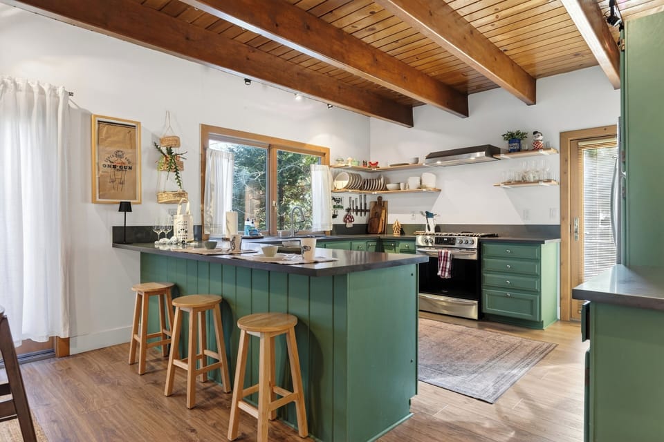 Bright, open kitchen with rustic beams, open shelving, and a cozy island—perfect for coffee and slow mountain mornings.
