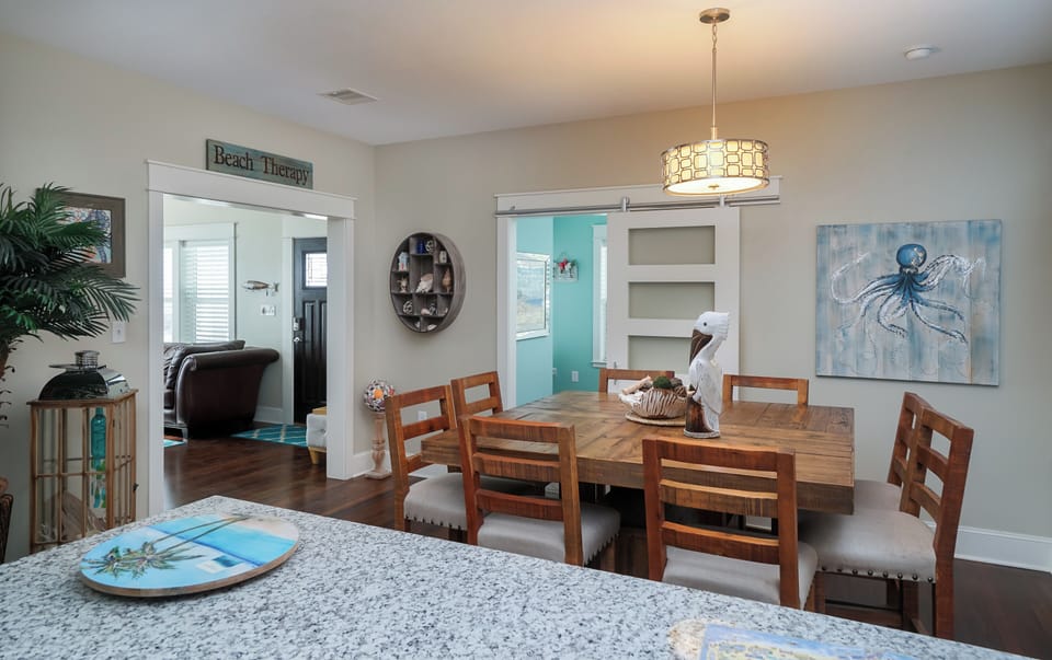 Bright dining room with coastal lighting and open floor plan for gatherings in Galveston vacation home.