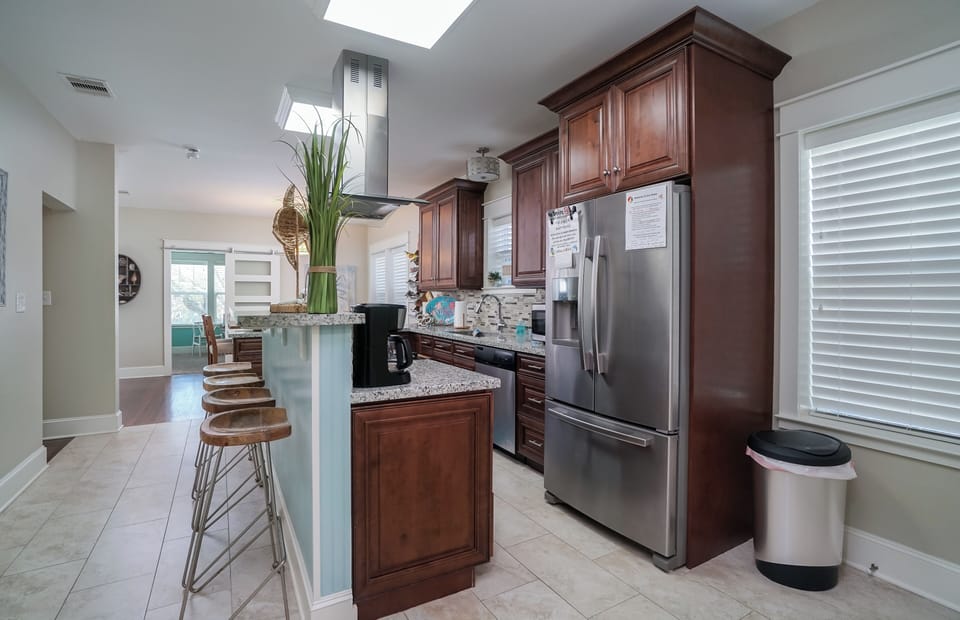 Open kitchen layout with plenty of cabinet space and stainless refrigerator in Galveston beach house.
