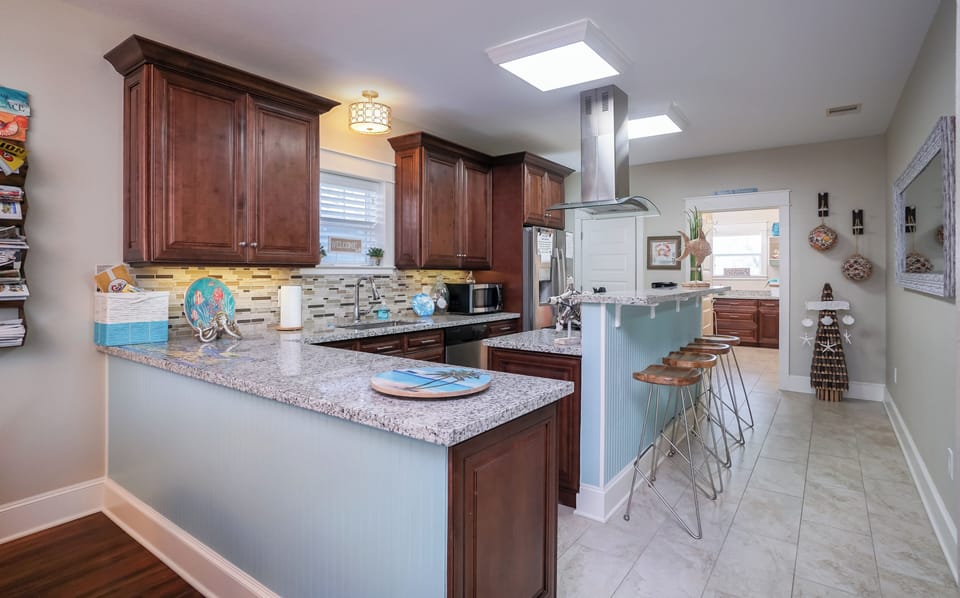 Modern kitchen with spacious island and stainless appliances ideal for cooking during your Galveston stay.