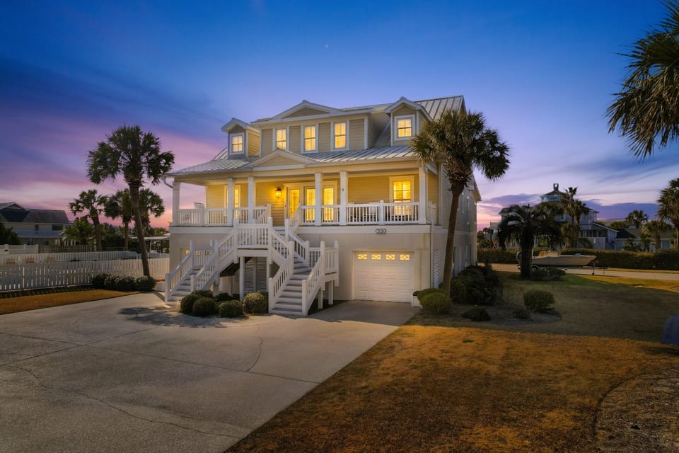 A beautiful coastal vacation home surrounded by swaying palm trees captures the essence of tropical paradise at twilight.
