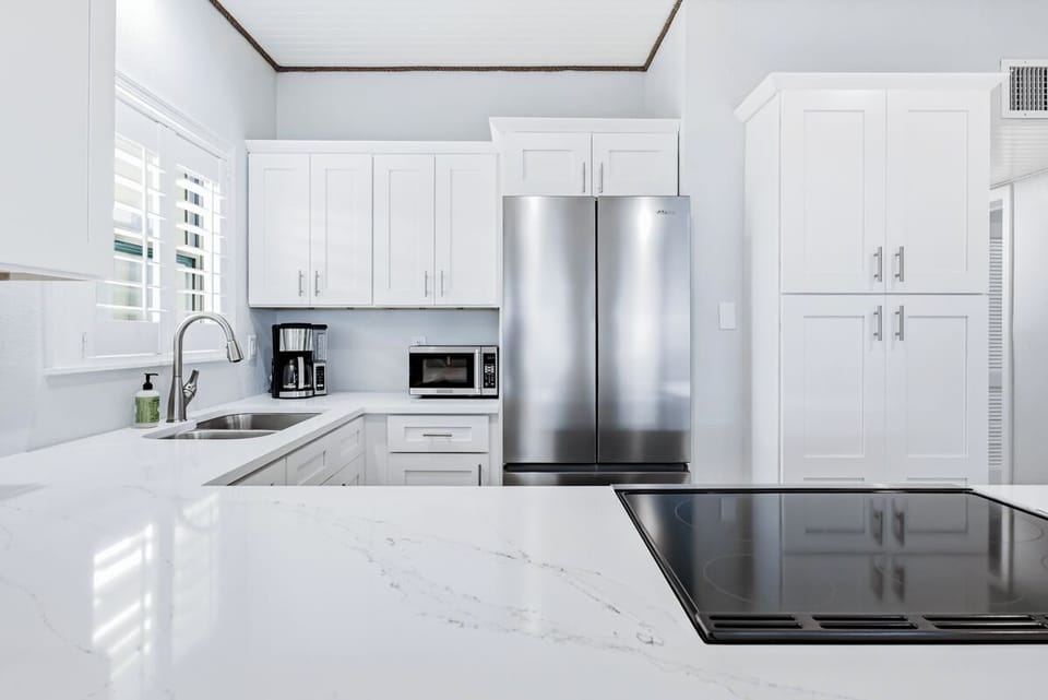 You'll love cooking in this pristine white kitchen with stainless appliances, quartz countertops, and everything you need for memorable meals.
